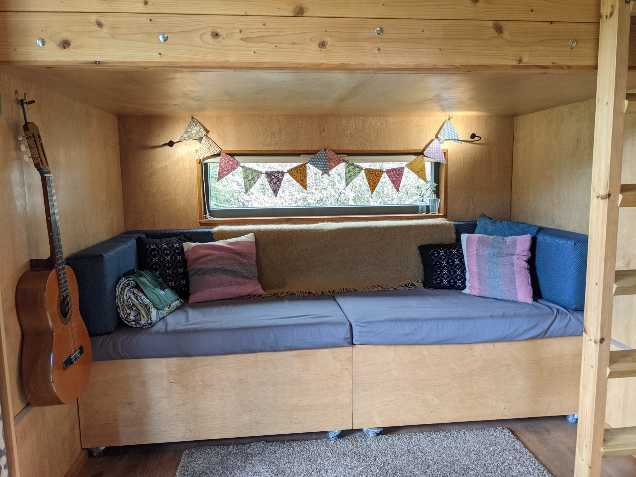 Seating area that converts into a kids bed underneath the platform double bed access by the ladder in the right of the image.